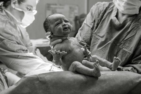 New born baby being held up for mother to see