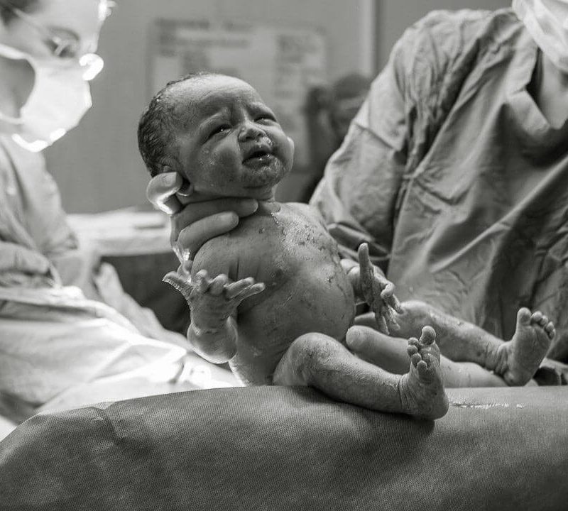 New born baby being held up for mother to see